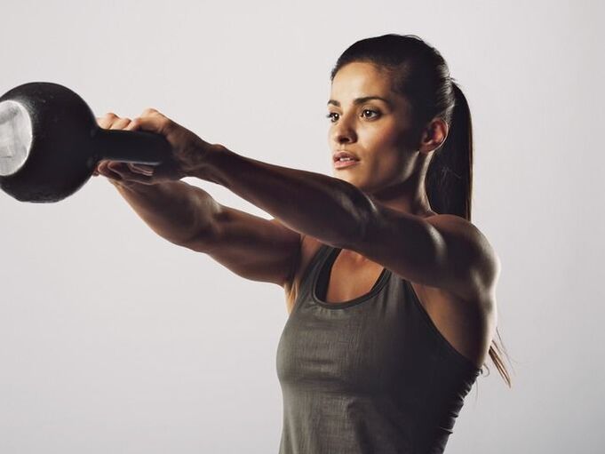 Unha nena realiza un exercicio para agrandar os seus peitos usando un kettlebell
